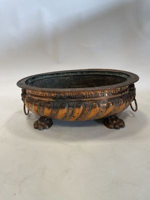 an old metal bowl with a handle on a white surface