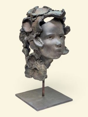sculpture représentant la tête d'une femme posée sur un socle, avec une fleur dans les cheveux