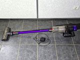 a purple corded vacuum on the floor next to a wall