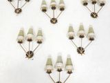six white and gold wall sconces mounted on a white wall
