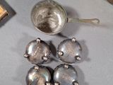 five silver bells sitting on a table next to a cup