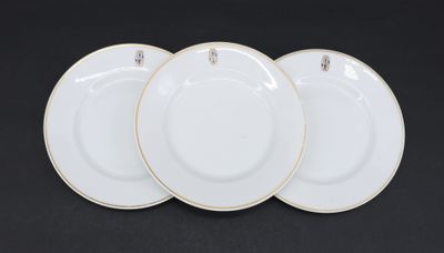 three white plates with gold rims on a black background
