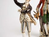 two figurines of a man and a woman standing next to each other