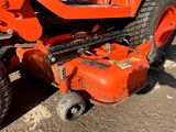 an orange lawn mower that is parked in the dirt