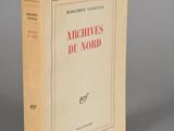 un vieux livre posé sur une table à côté d'un mur gris