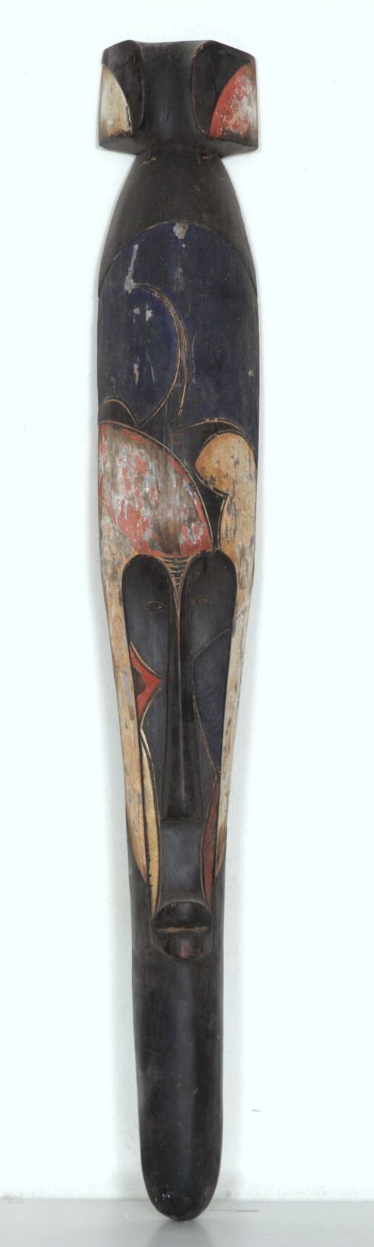 AFRIQUE. Masque de forme allongée en bois sculpté et peint en noir, ocre, rouge et bleu. L_106 cm