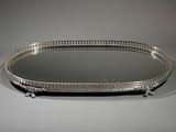an oval silver tray with a mirror on top of it