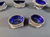 four blue glass bowls and a silver plate on a table