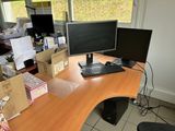 a desk with two monitors and a keyboard in front of a window