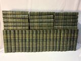 une pile de vieux livres verts posée sur une table blanche