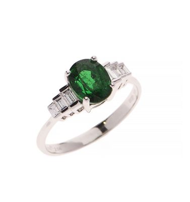 un gros plan d'une bague sertie d'une pierre verte et de pierres taillées en baguette