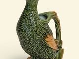 a green bird that is sitting on top of a vase