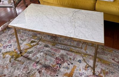 une table basse avec un plateau en marbre posée sur un tapis dans un salon
