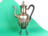 a silver tea pot sitting on a green surface