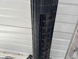a black tower fan sitting on the floor next to a ladder