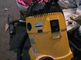 un aspirateur jaune posé par terre à côté d'un tas de vêtements