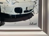 un tableau représentant une voiture de sport blanche, dans un cadre argenté