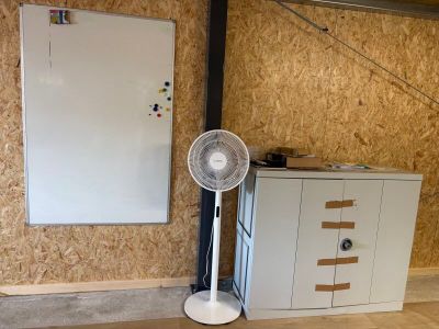 une photo d'une pièce avec un ventilateur et un tableau blanc