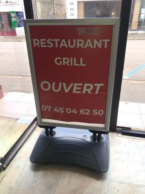 a sign that says restaurant grill ouvertt on the sidewalk