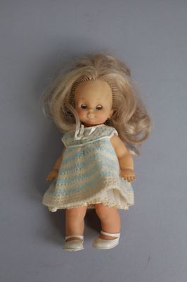 une petite poupée aux cheveux blonds et vêtue d'une robe bleue