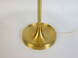 a gold table lamp that is on a white table