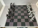 a black and white chess board with silver figurines on it