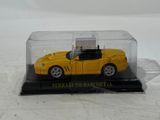 a yellow toy car in a clear case on a white surface