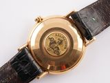 a gold wrist watch with a black leather strap