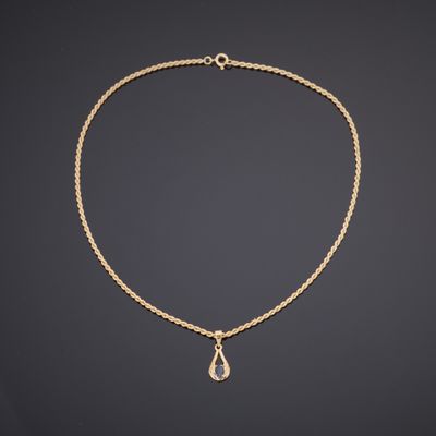 un collier en or avec un pendentif en forme de larme suspendu à une chaîne