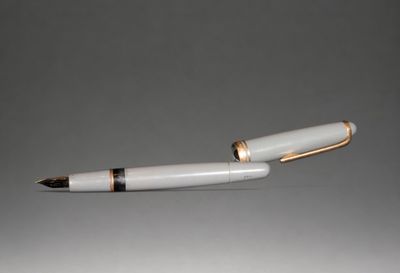 a white pen with gold trim and a black tip