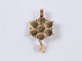 a gold pendant with a flower design hanging from it ' s side
