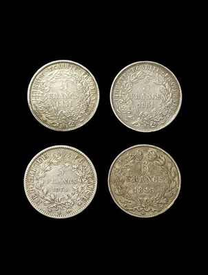 four different types of silver coins on a black background