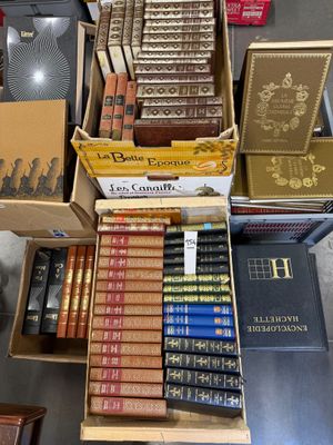 de nombreux livres rangés dans des cartons posés sur une table dans une pièce