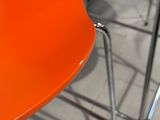 un gros plan d'une chaise orange avec une assise noire