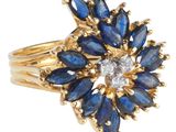 gros plan d'une bague en or avec des pierres bleues et blanches
