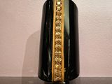 un vase noir orné d'une bordure dorée posé sur une table noire