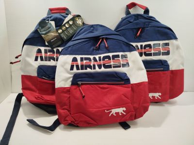 Trois sacs à dos rouges, blancs et bleus sont alignés sur une table