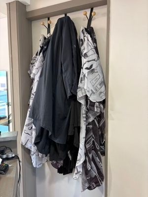 a coat rack with clothes hanging on it next to a mirror