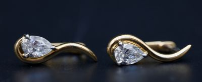 une paire de boucles d'oreilles en or et diamants posée sur un fond noir