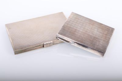 two silver cigarette cases sitting side by side on a white surface