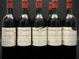 quatre bouteilles de vin rouge sont alignées sur une surface noire