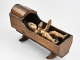 sculpture of a baby in a wooden cradle on a white background