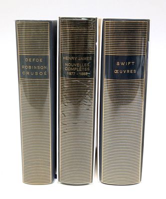 trois livres superposés sur une surface blanche