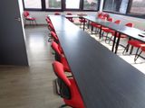 une longue table avec des chaises rouges au milieu d'une pièce