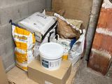 a bucket of paint on a pallet next to a box of cement