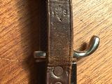 une ceinture en cuir marron avec une boucle en métal posée sur une table en bois