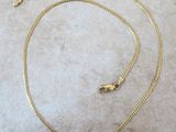 gros plan d'un collier en or sur une surface blanche