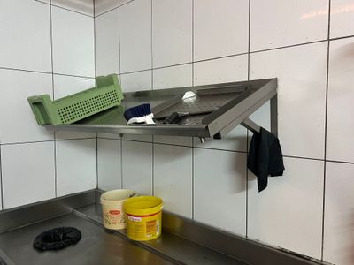 un évier de cuisine surmonté d'une étagère en métal