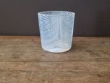 a glass cup on a wooden table with a white wall in the background
