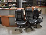 deux fauteuils de bureau en cuir noir placés devant un bureau